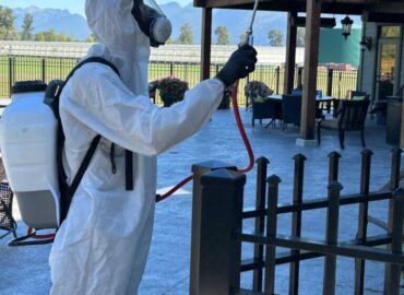 Pest control technician in protective gear spraying exterior of a property in Abbotsford BC